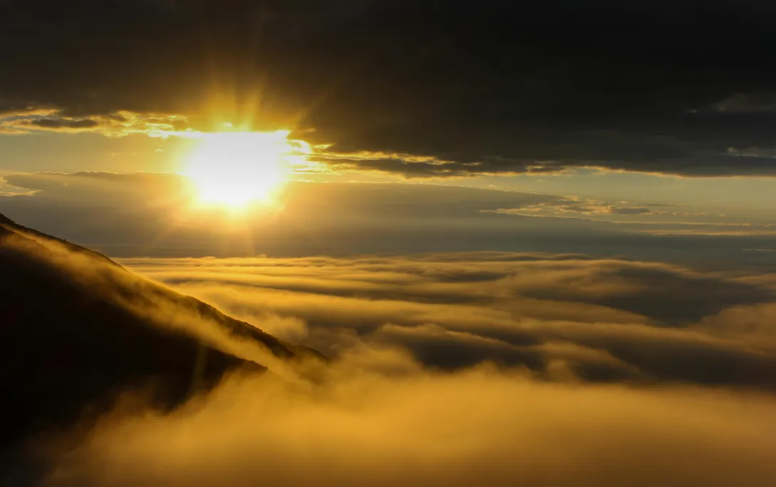 Fotografia de um por de sol tirada no topo de uma montanha.